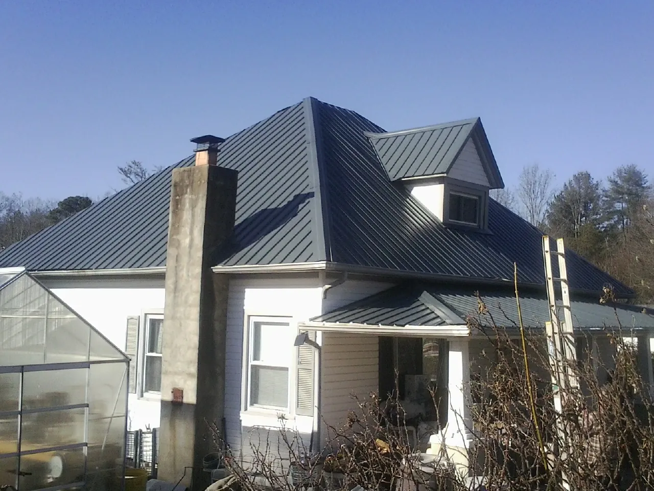 Dark blue standing seam metal roof on a white farmhouse with dormer — Slate & Tile Roof Repair by Roofing Brothers in Lehi