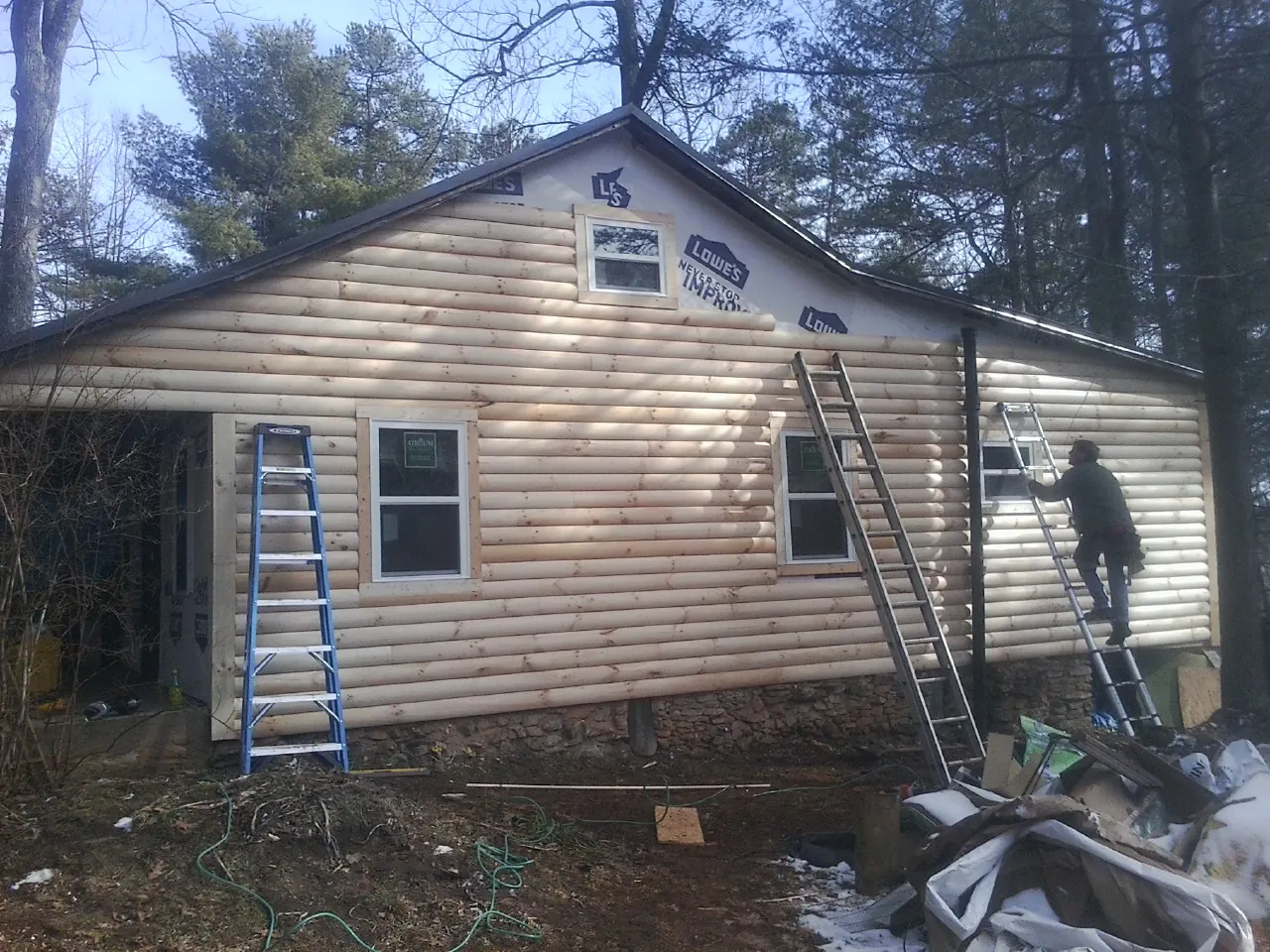 Ladders set against fresh log siding during an exterior remodel in Lehi