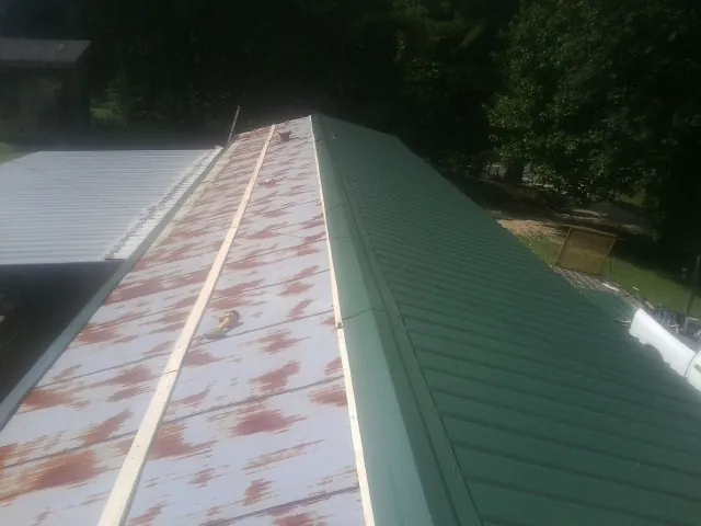 Old rusted panels beside newly installed green metal roofing — Wind Damage Roof Repair by Roofing Brothers in Lehi