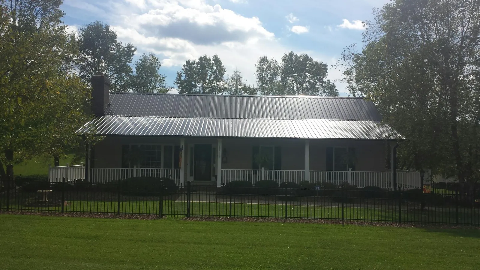 Gray metal roof on a brick ranch with a full width front porch — Gutter Guard Installation work by our crew in Lehi