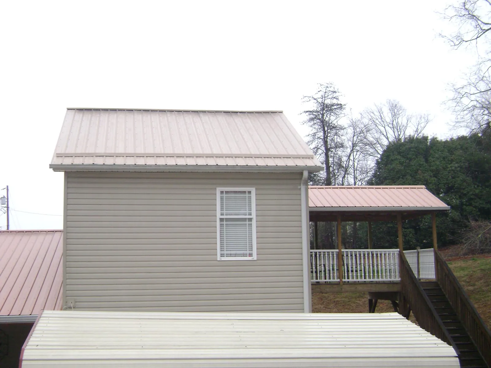 Tan metal roofs on a two story addition and attached porch, from a Roof Replacement job in Lehi