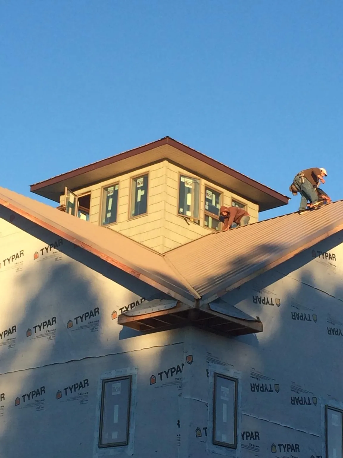 Roofers working around a rooftop cupola on a new metal roof at sunset — Roof Waterproofing in Lehi by Roofing Brothers